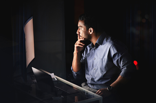 Night, computer or businessman thinking of idea, planning strategy or reading email on research in office. Tech, laptop or creative man for trading, SEO analytics or working on innovation web design