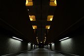 Dark tunnel with turned-on lamps on the ceiling
