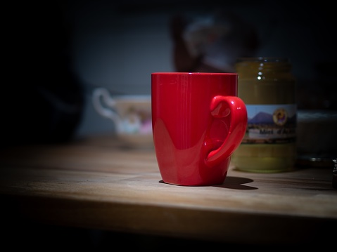 A selective focus shot of a red mug on a wooden surface