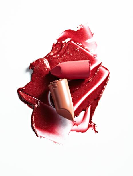 split and smeared lipsticks and lip glosses on a white backgroun