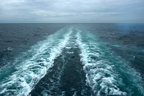 The foamy waves on the surface of the water behind the cruise ship