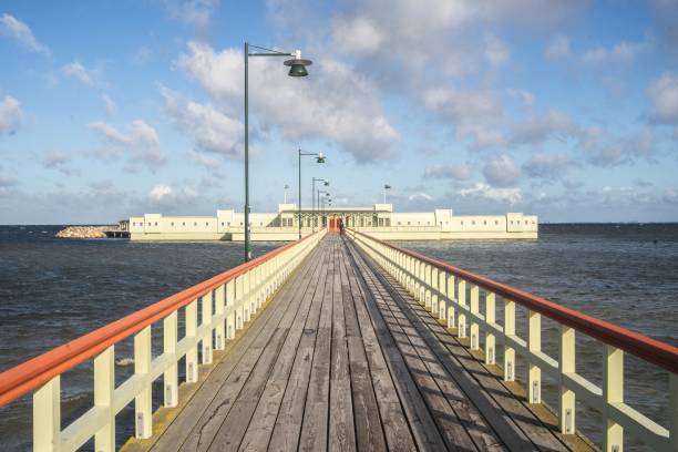 istock Pier surrounded by the sea and buildings under a cloudy sky and sunlight 1438873281