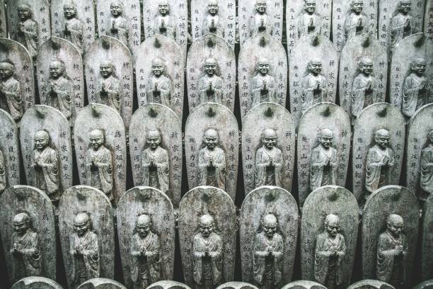 Row of Buddhist Jizo statues in a temple in Japan with hieroglyphs on them A row of Buddhist Jizo statues in a temple in Japan with hieroglyphs on them kannon bosatsu stock pictures, royalty-free photos & images
