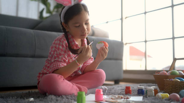 little girl sitting and drawing easter eggs