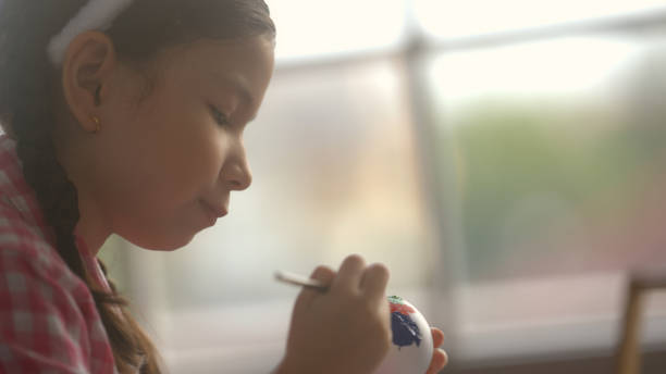 little girl sitting and drawing easter eggs