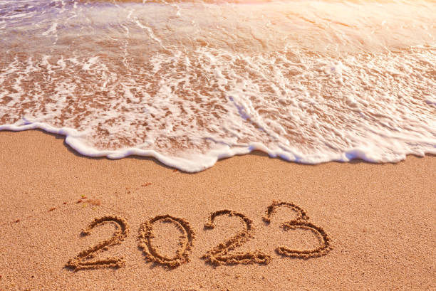 2023 year written on sandy beach sea at sunny day stock photo