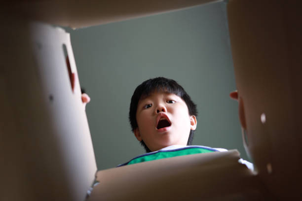 istock Surprised young Asian boy looking into a Box 1438875782