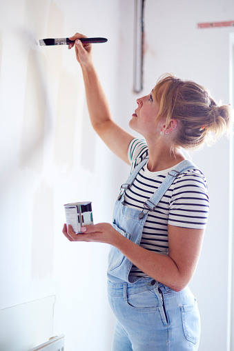 Woman Decorating Room In House Painting Tester Paint Colour Strips On Wall