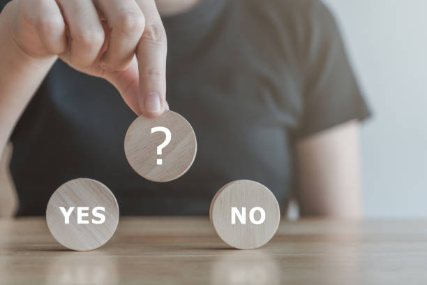 istock Think with Yes Or No choice.Test question. Choice hesitate, opposition, opponent view. making decision. Woman hand holding question mark on wooden circle with YES and NO text. 1438885359