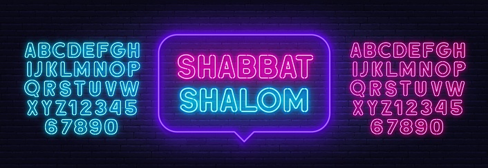 Shabbat Shalom neon sign in the speech bubble on brick wall background . Pink and blue neon alphabets.