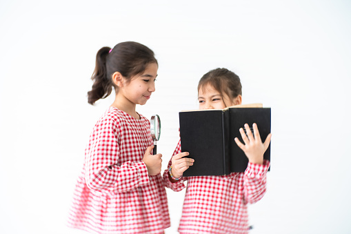 Brother and sister reading a book Against white Background
