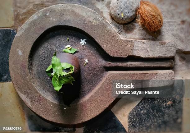 A Small Black Shivalingam Made From Stone And Covered In Flowers And Bel Leaves Stock Photo - Download Image Now