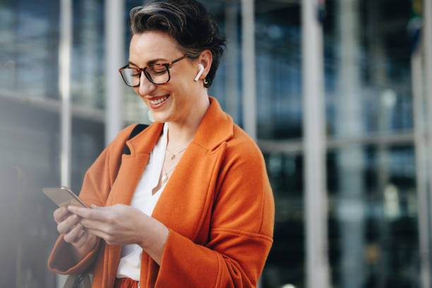 웃는 사업가가 휴대폰으로 문자 메시지를 읽고 있다 - businesswoman business mobile phone business person 뉴스 사진 이미지