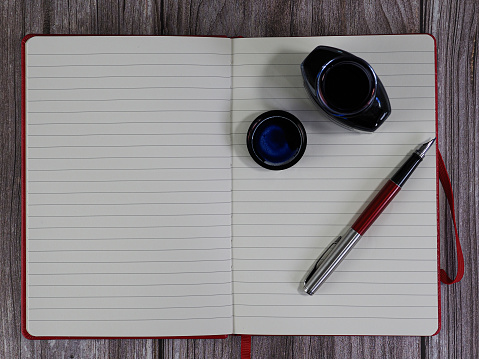 open notebook with pen and inkwell for writing. on wooden background. space to write. top view.