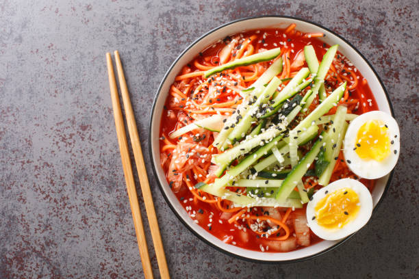 Korean spicy cold noodles Bibim Guksu closeup in the bowl. Horizontal top view Korean spicy cold noodles Bibim Guksu closeup in the bowl on the table. Horizontal top view from above Kimchi stock pictures, royalty-free photos & images