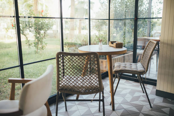 大きな窓の近くにテーブルと木製の椅子が立っている居心地の良い明るいインテリア。
