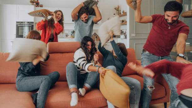 Happy friends having a funny pillow fight stock photo