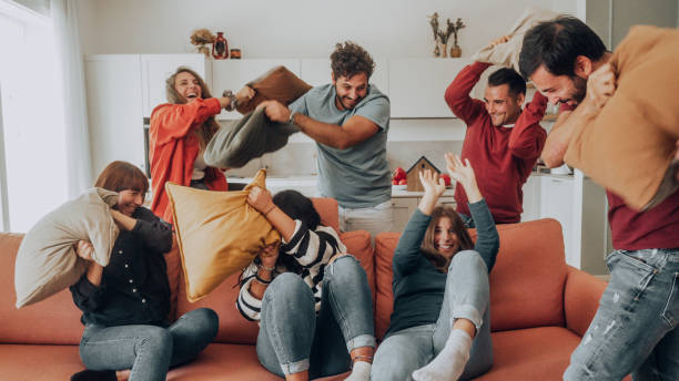 istock Happy friends having a funny pillow fight 1438901796