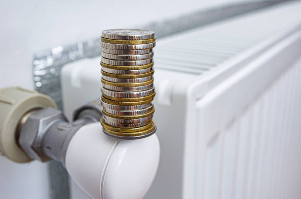 istock Stack of coins on a radiator heating thermostat at home. 1438903930