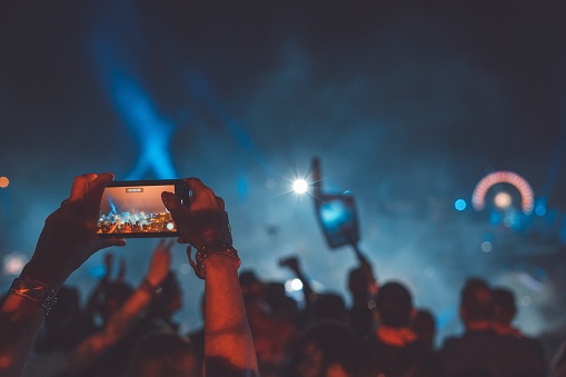 A person taking a video of a legendary concert at a club
