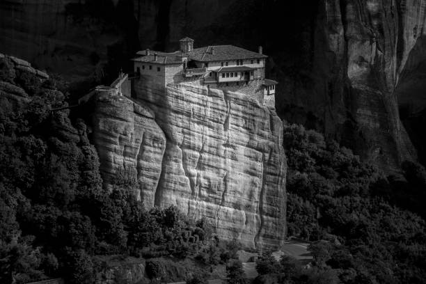 Monastery of the Holy Trinity on a rock surrounded by forests and hills under sunlight in Greece The Monastery of the Holy Trinity on a rock surrounded by forests and hills under sunlight in Greece black and white travel travel destinations monk stock pictures, royalty-free photos & images