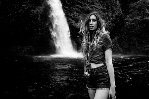 An attractive Caucasian woman standing against the Multnomah Falls in Oregon, Portland, USA