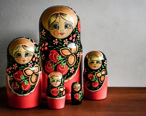 A wooden table with Russian nesting Matrioshka dolls with a white background