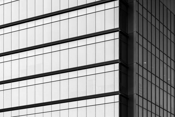 istock Greyscale of a modern building with glass windows under sunlight 1438904887