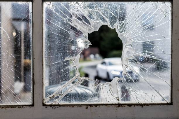istock Broken glass window surrounded by rusty old frames with cars and a park on the background 1438904953