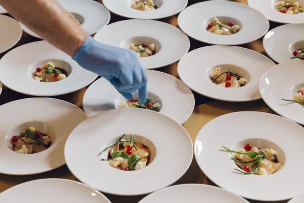 istock Cook adding ingredients on a dish filled in white serving plates in a restaurant 1438906207