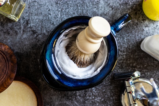 High angle shot of shaving cream and brush on a grey surface