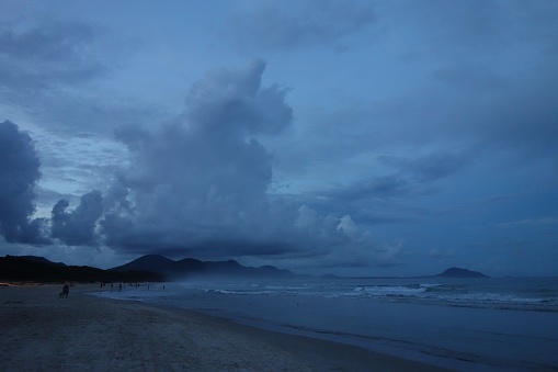 A beautiful shot of a beach shore under a dark blue cloudy sky