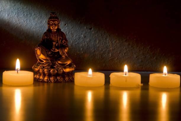 istock Buddha statue and burning candles reflecting on a black surface 1438906837