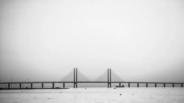 A beautiful shot of the Öresundsbron bridge over the sea with a foggy background