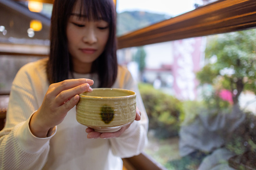 Woman wiping the edge of cup of Matcha tea. It’s the way of tasing matcha tea.