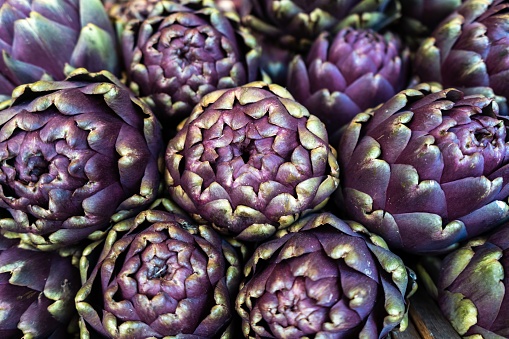 A closeup shot of purple artichokes neatly stacked in a market