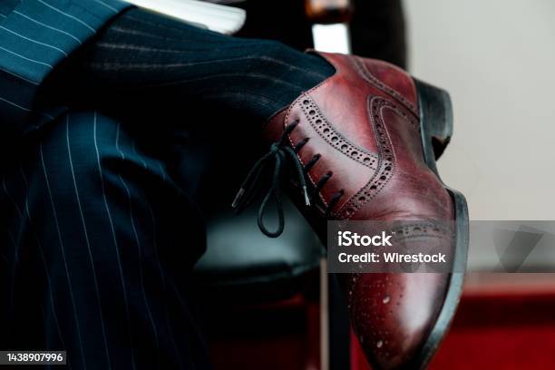 Closeup Of A Brogue Shoe On A Person Sitting With Crossed Legs Under The Lights Stock Photo - Download Image Now