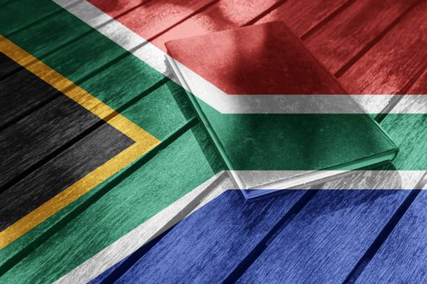 flag of south africa layered over a book laid on a wooden surface - hardbound imagens e fotografias de stock