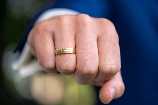 A closeup of the fist of a man with a wedding ring on his ring finger