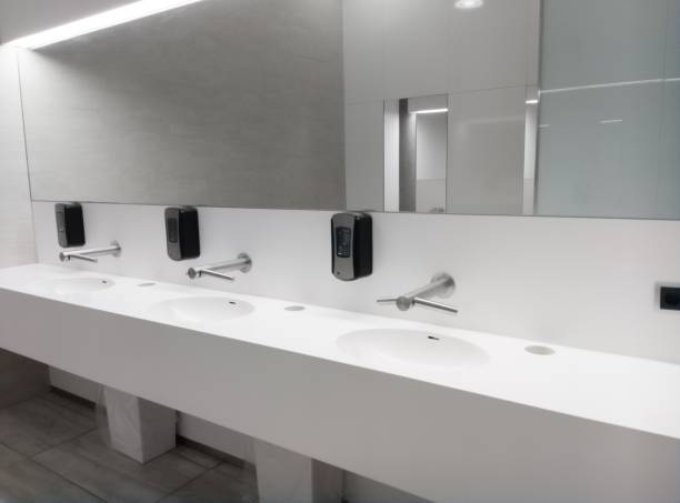 istock Modern public bathroom with white interior and a mirror with sinks 1438909461