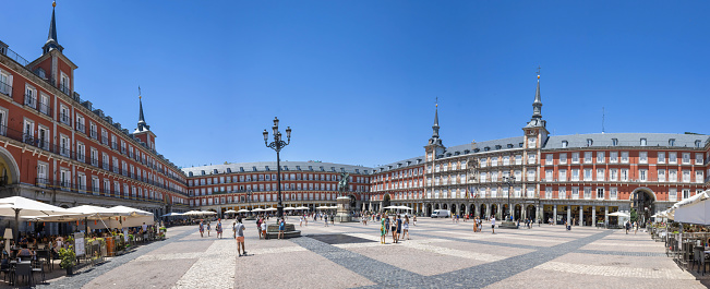 Madrid, Spain - July 10, 2022: Cafes & restaurants line the arches of this stately square with Philip III's statue in the center.