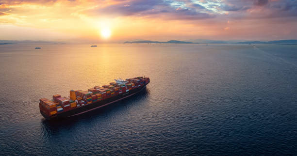 istock A cargo container ship sails over calm ocean into a golden sunset 1438915495