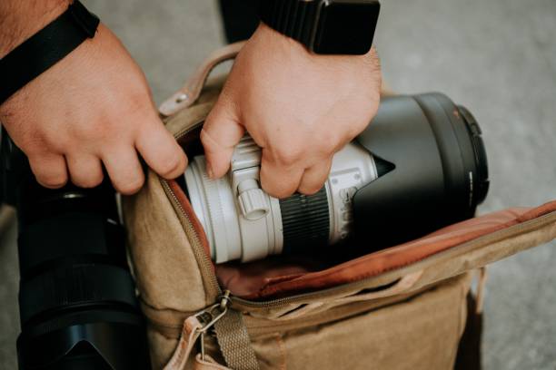 istock Photographer pulling out a white camera lens from a camera bag 1438920248