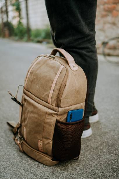 istock Brown canvas camera bag with a smart phone in the side pocket, on the ground 1438920251