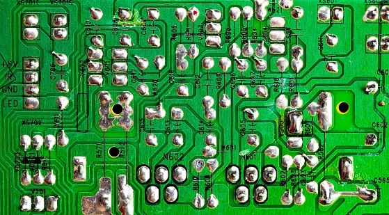 Macro Close up of printed wiring on old green PC circuit board..