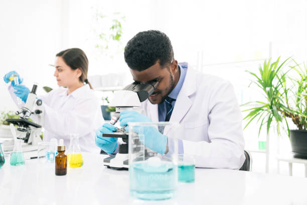 istock Young African black man scientist looking through a microscope in a laboratory for doing research. Students analyze biochemical by microscope research in the lab for discovering new medicine. 1438921486