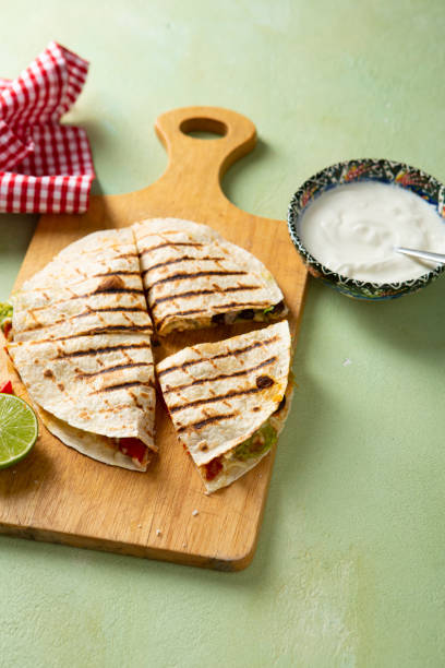 Close up of Sliced grilled quesadilla with meat and cheese lime guacamole on cutting board stock photo