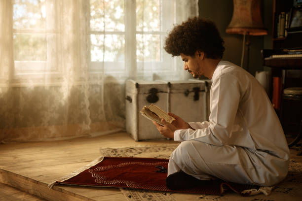 istock Young Muslim reading from Quran while praying at home. 1438923815