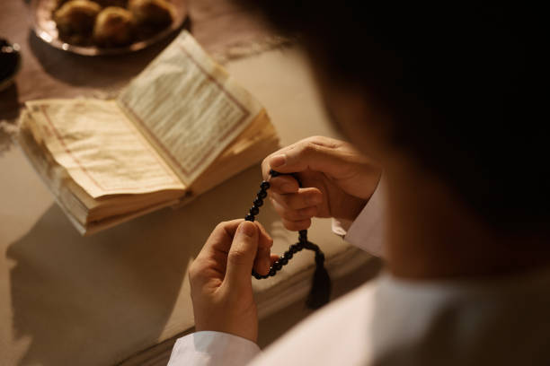 istock Close up of Middle Eastern man holding misbaha beads while reading Quran. 1438923911