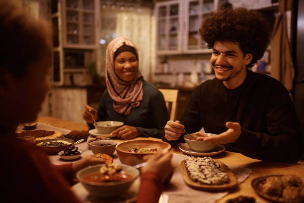 istock Happy Middle Eastern man talking to his family while eating dinner at dining table. 1438924063